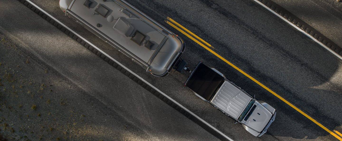 A bird's-eye view of the 2023 Jeep Gladiator Overland towing a camper trailer.