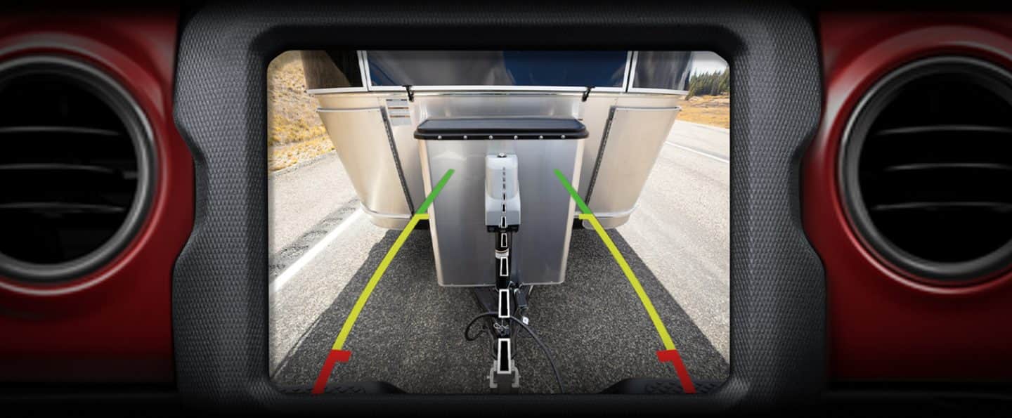 The 8.4-inch Uconnect touchscreen on the 2023 Jeep Gladiator displaying the output of the ParkView Rear Back Up Camera as it nears the trailer behind it.