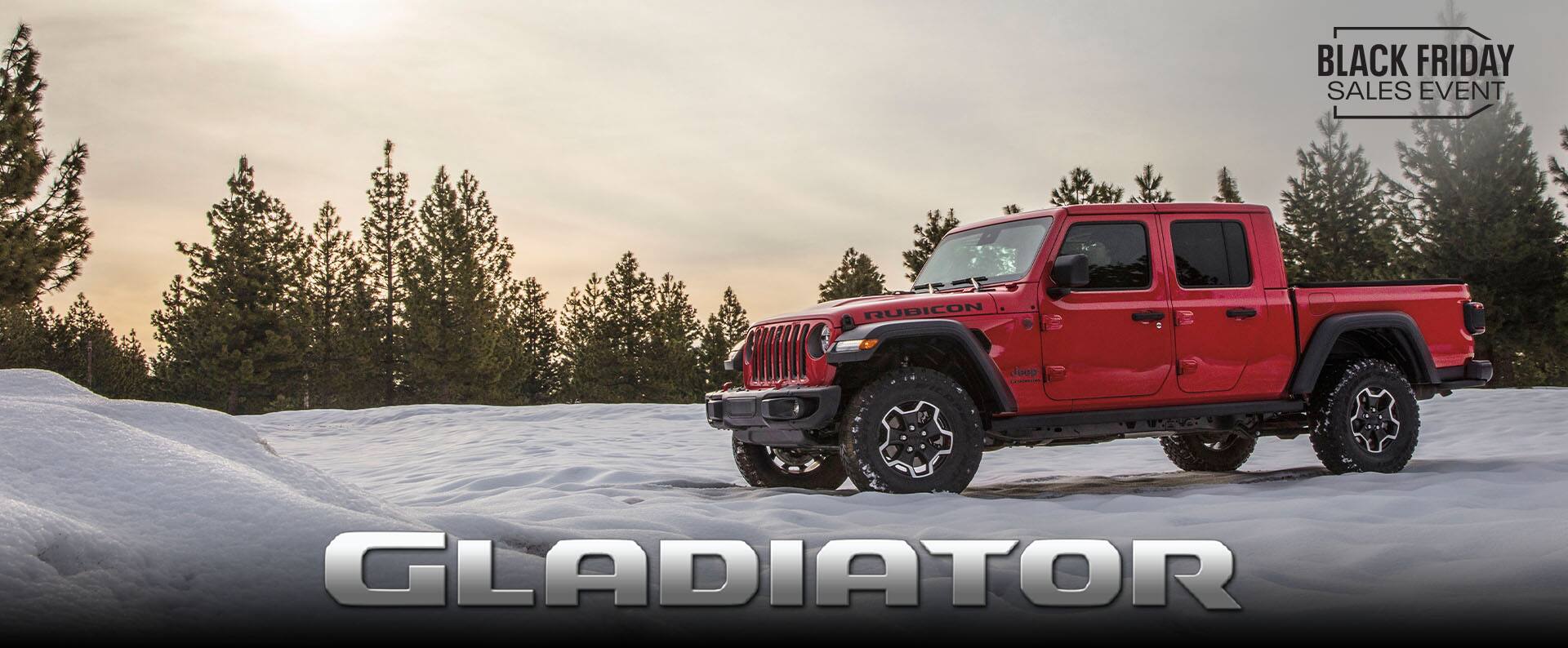 A driver-side profile of a red 2023 Jeep Gladiator Rubicon parked on the snow, off-road. The Black Friday Sales Event. Gladiator.