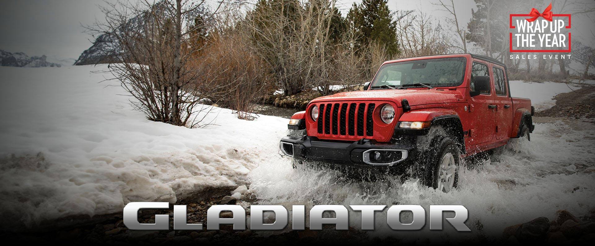 A red 2023 Jeep Gladiator Sport S fording through an icy stream, off-road. Wrap Up The Year Sales Event. Gladiator.