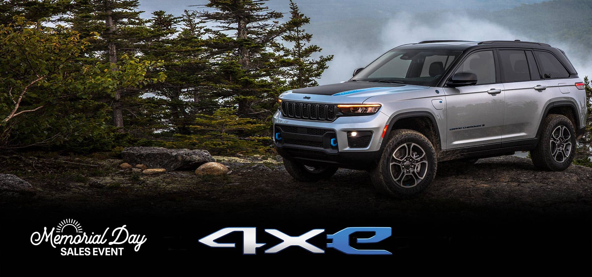 Un Jeep Grand Cherokee Trailhawk 4xe 2023 plateado estacionado en un afloramiento rocoso en un bosque, con montañas rodeadas de niebla de fondo. Grand Cherokee. Logo del evento de ventas por el Día de los Caídos.