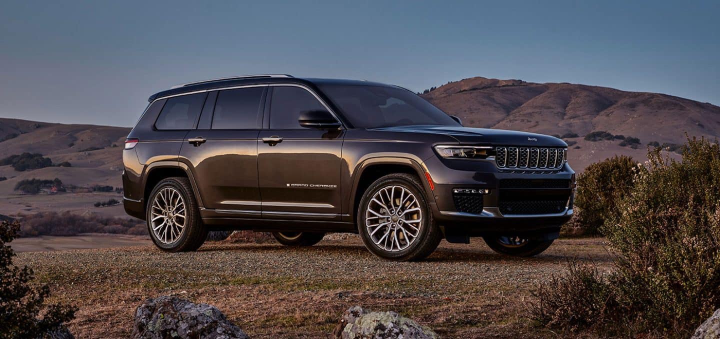 Display The 2023 Jeep Grand Cherokee Summit Reserve parked off-road in the desert with a mountain rising in the distance.