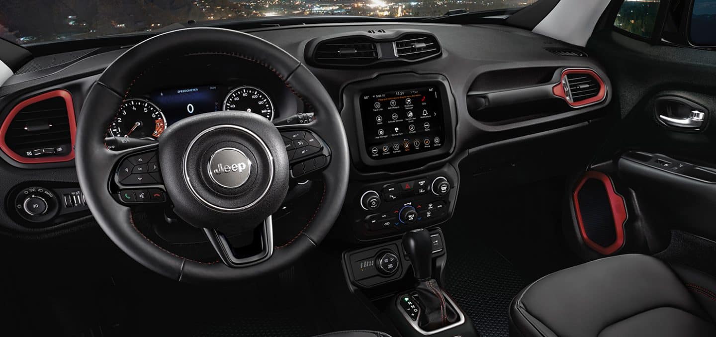 Display The interior of the 2023 Jeep Renegade focusing on the steering wheel, Digital Cluster Display, Uconnect touchscreen, center stack and dashboard.