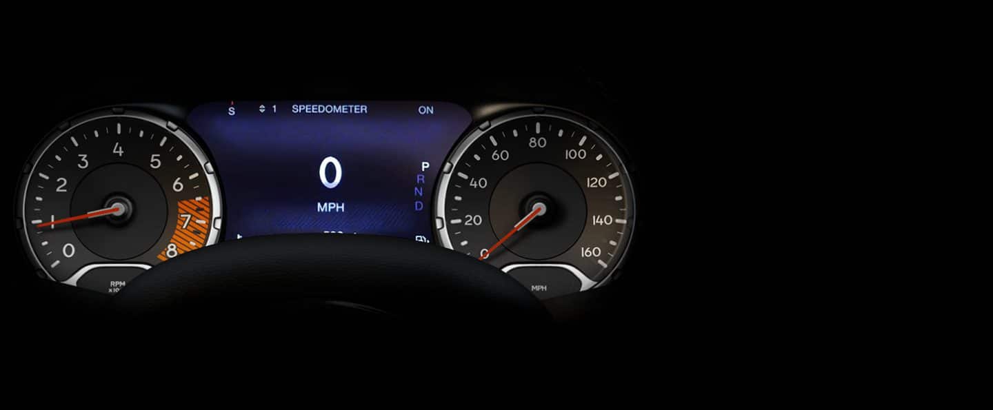 The driver information digital cluster display in the 2023 Jeep Renegade, positioned between the analog tachometer and analog speedometer.