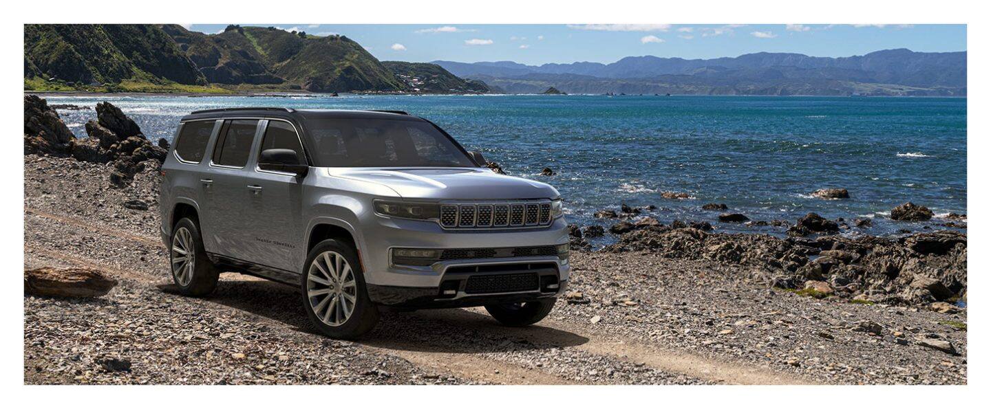 The 2023 Grand Wagoneer Series III parked on a rocky beach beside the water.