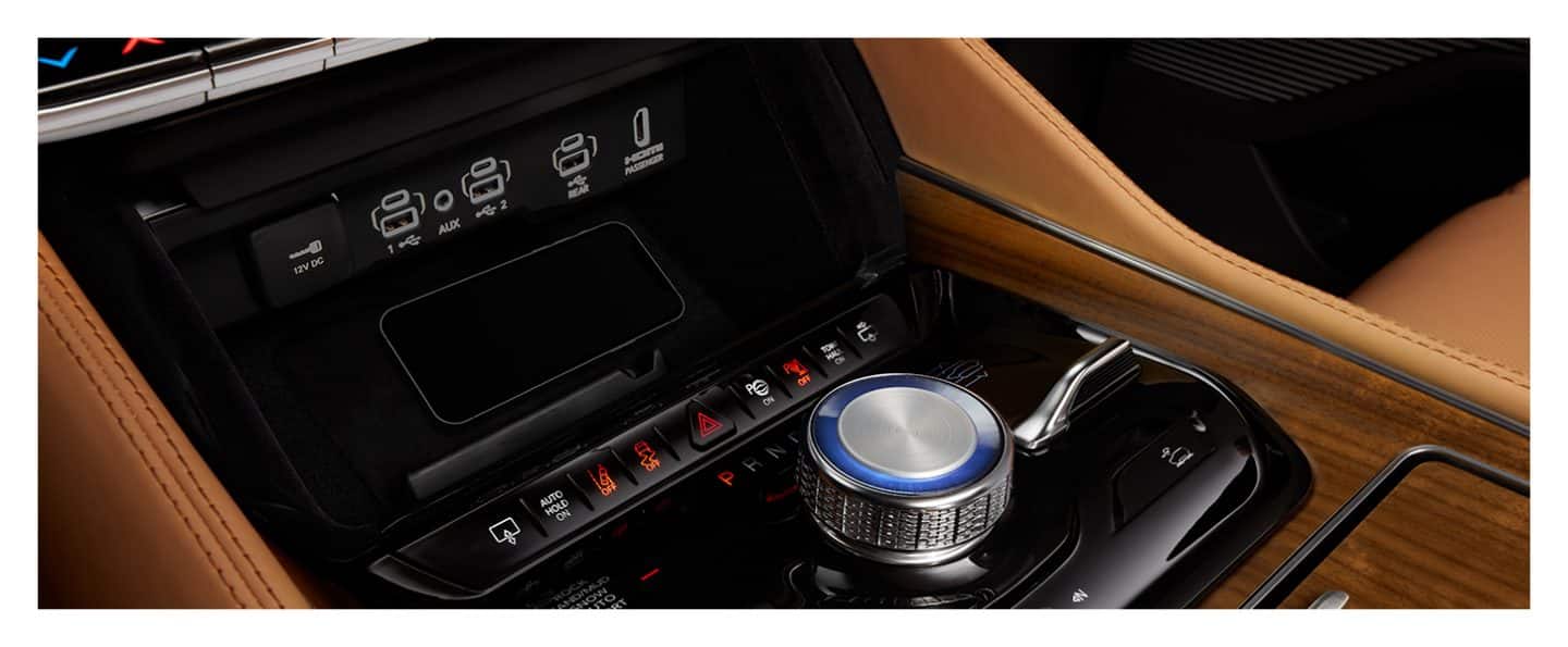 A smartphone in the wireless charging pad in the 2023 Grand Wagoneer Series III, located in the front console between the rotary shifter and the auxiliary input ports.