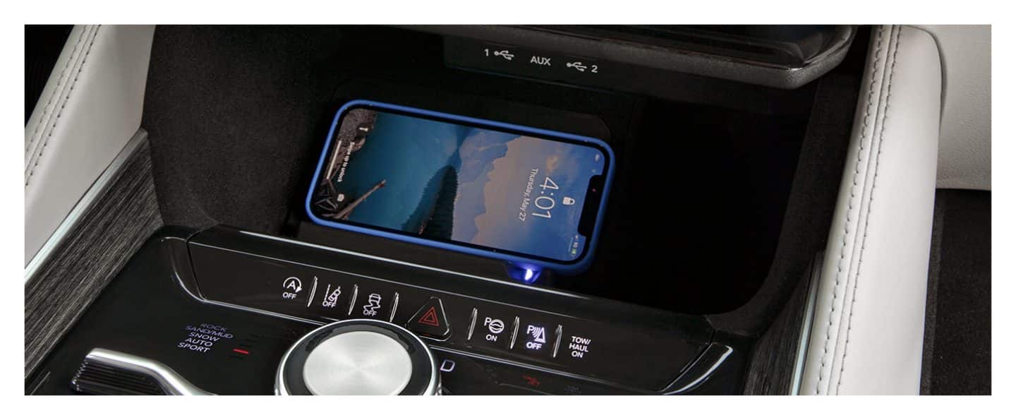 A smartphone in the wireless charging pad in the 2023 Wagoneer, located in the front console between the rotary shifter and the auxiliary input ports.