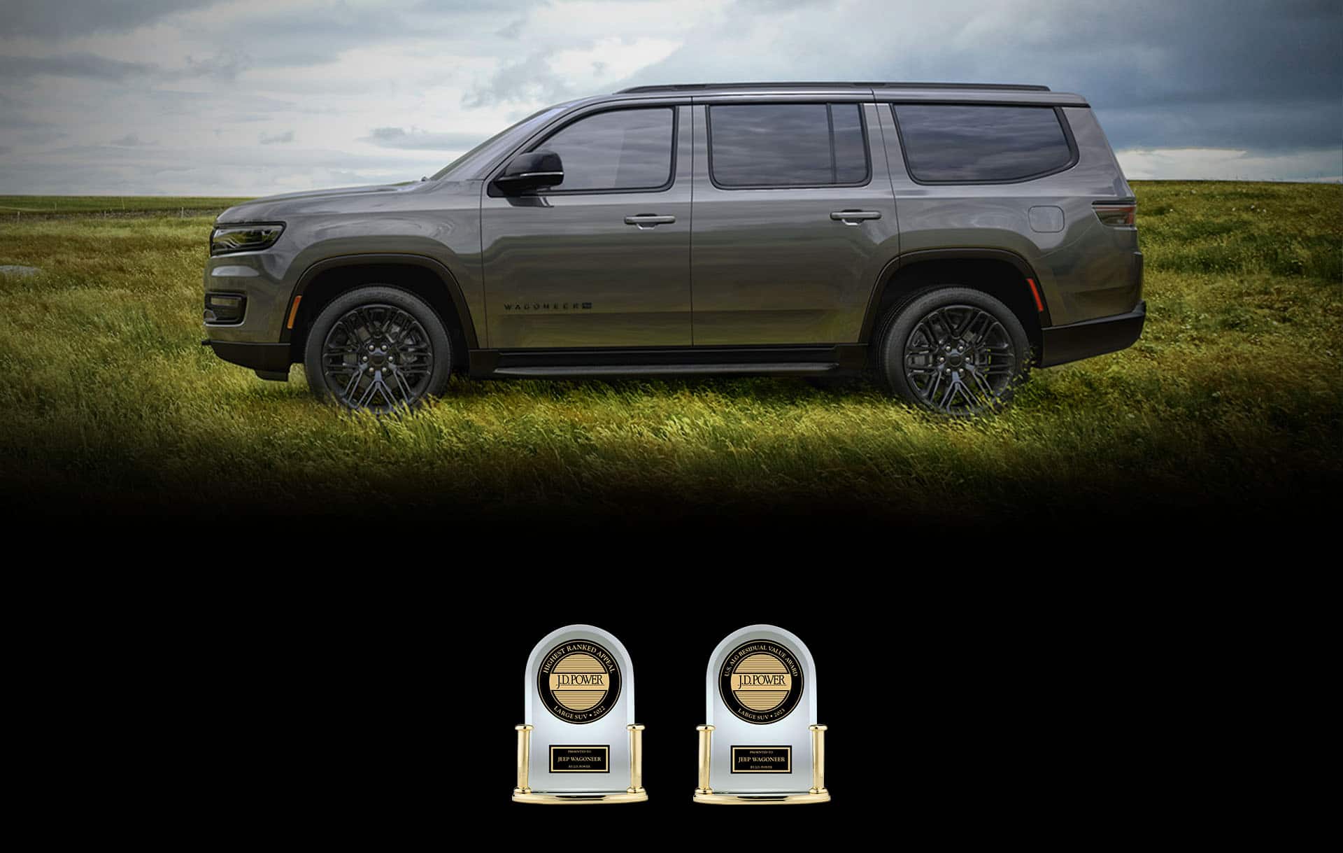 A driver-side profile of a gray 2023 Jeep Wagoneer Carbide parked on a grassy field with a stormy sky overhead. Two J.D. Power Appeal trophies. One reads: Highest Ranked Appeal – Large SUV 2022; Presented to Jeep Wagoneer by J.D. Power. The other reads: Best ALG Residual Value Award – Large SUV 2023; Presented to Jeep Wagoneer by J.D. Power.