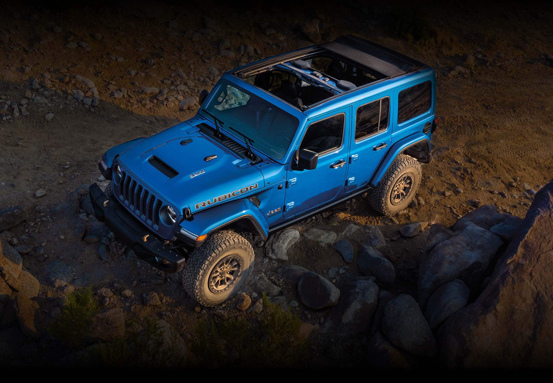 The 2023 Jeep Wrangler Rubicon 392 with its Sky One-Touch Power Top open as it is driven up a rocky slope.