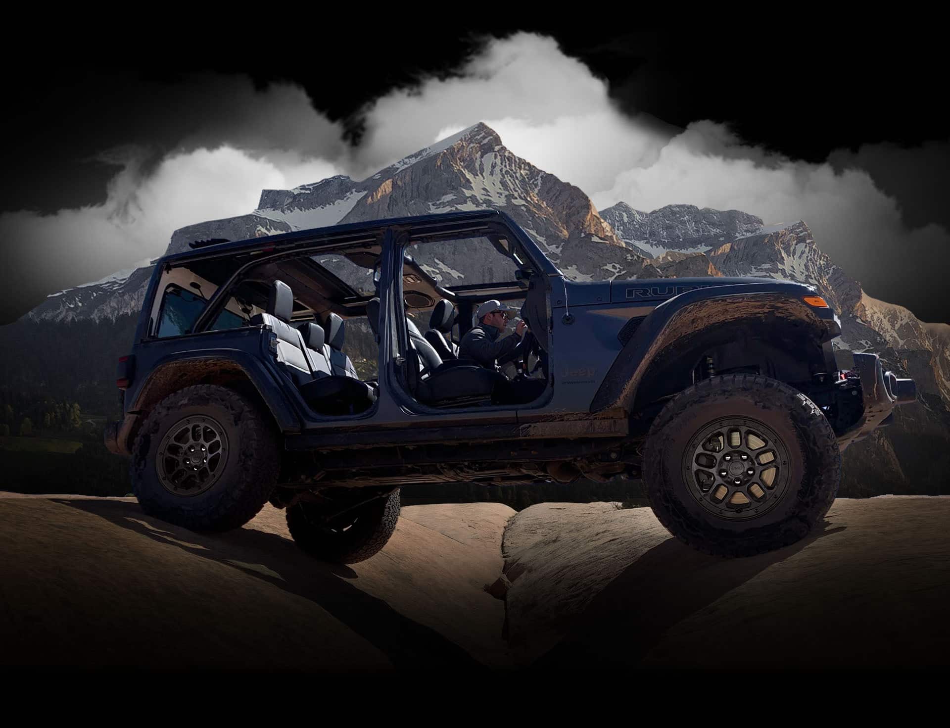 The 2023 Jeep Wrangler Rubicon 392 straddling two boulders as it's driven off-road with its doors off and top open.
