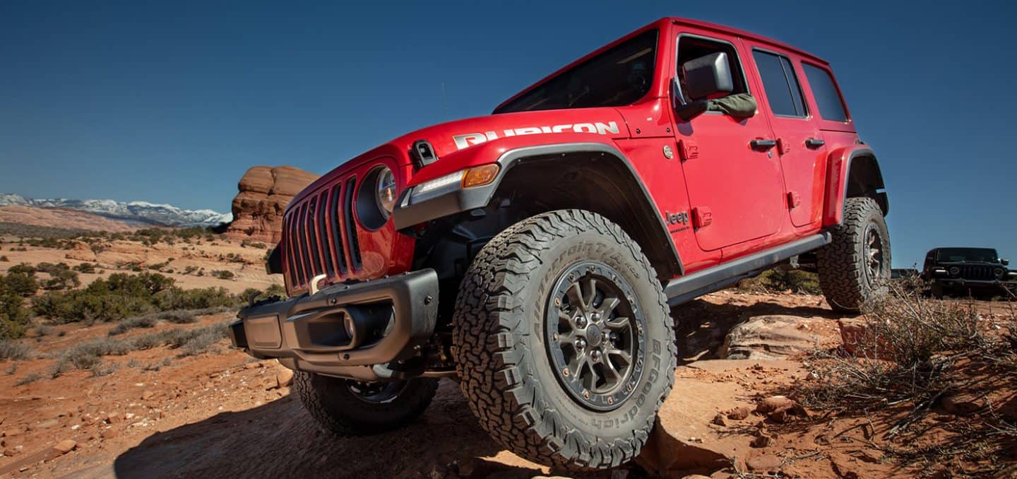 2023 Jeep Wrangler Rubicon in red driving through the high desert - Capability Image 1