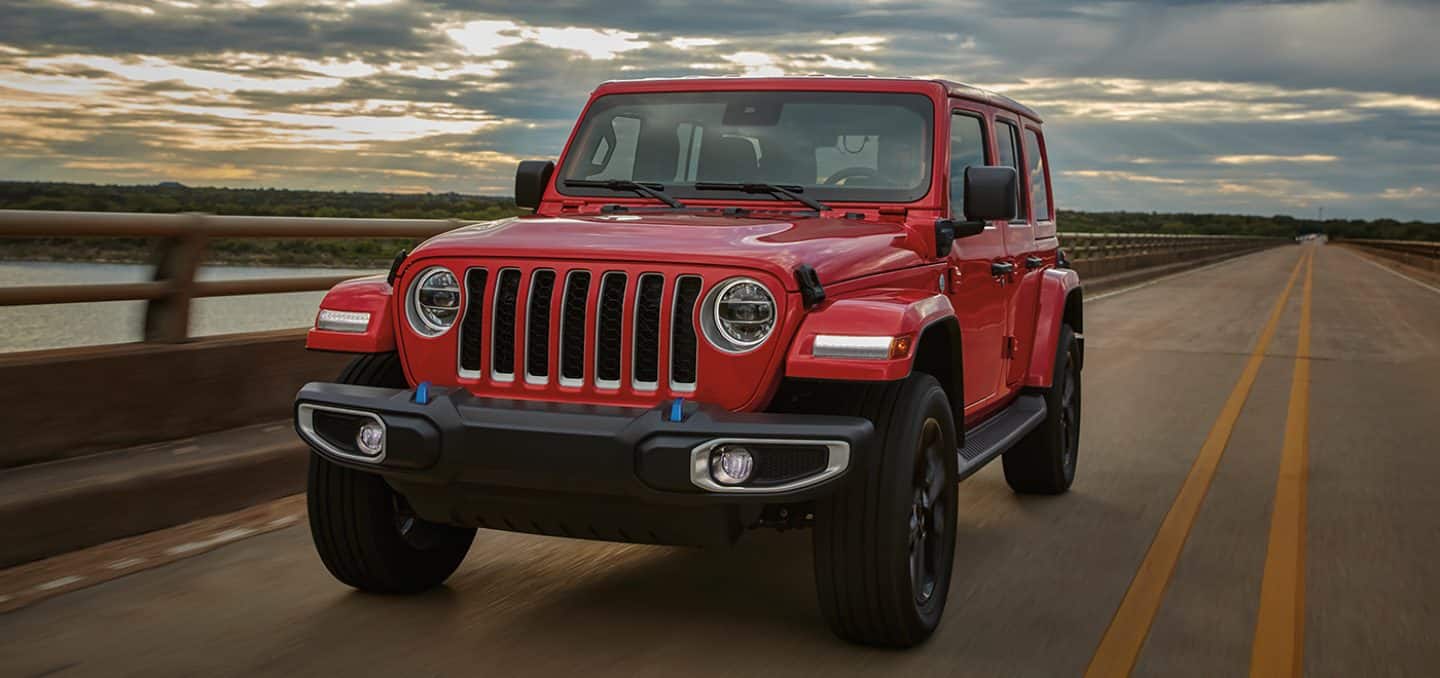 Display The 2023 Jeep Wrangler 4xe being driven on an open road at sunset.