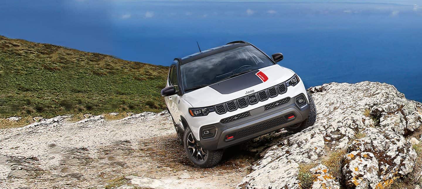 Un Jeep Compass Trailhawk 2024 estacionado horizontalmente en una colina empinada y rocosa.