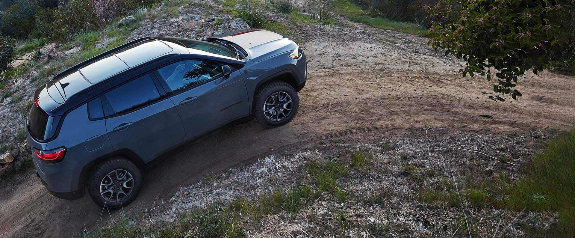 A 2024 Jeep Compass Trailhawk ascending a steep dirt trail off-road.