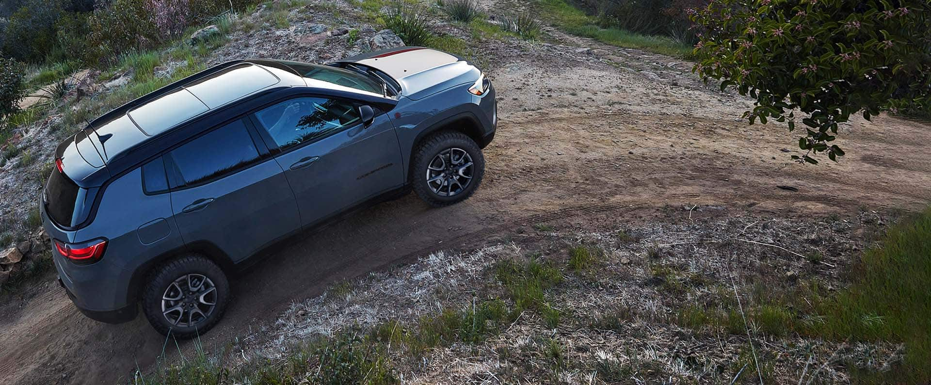 Un Jeep Compass Trailhawk 2024 asciende por un empinado camino de tierra.