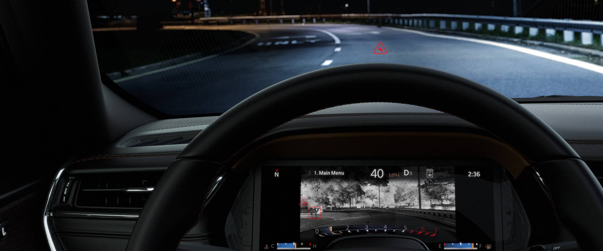 The interior of the 2024 Jeep Grand Cherokee from the driver's perspective, demonstrating through the windshield that the vehicle is being driven on a highway in the dark, as the Driver Information Digital Cluster displays a night vision image of the road ahead, revealing a deer near the roadway.