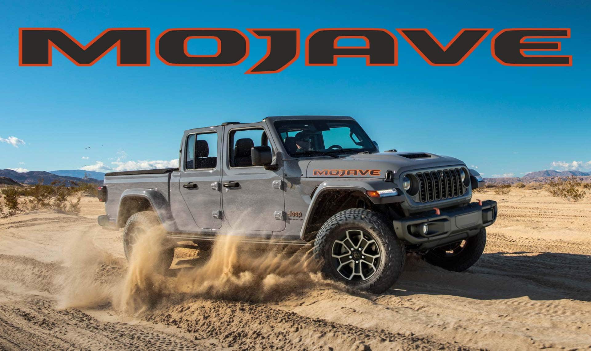 A gray 2024 Jeep Gladiator Mojave kicking up sand as it's driven off-road in the desert. Mojave.