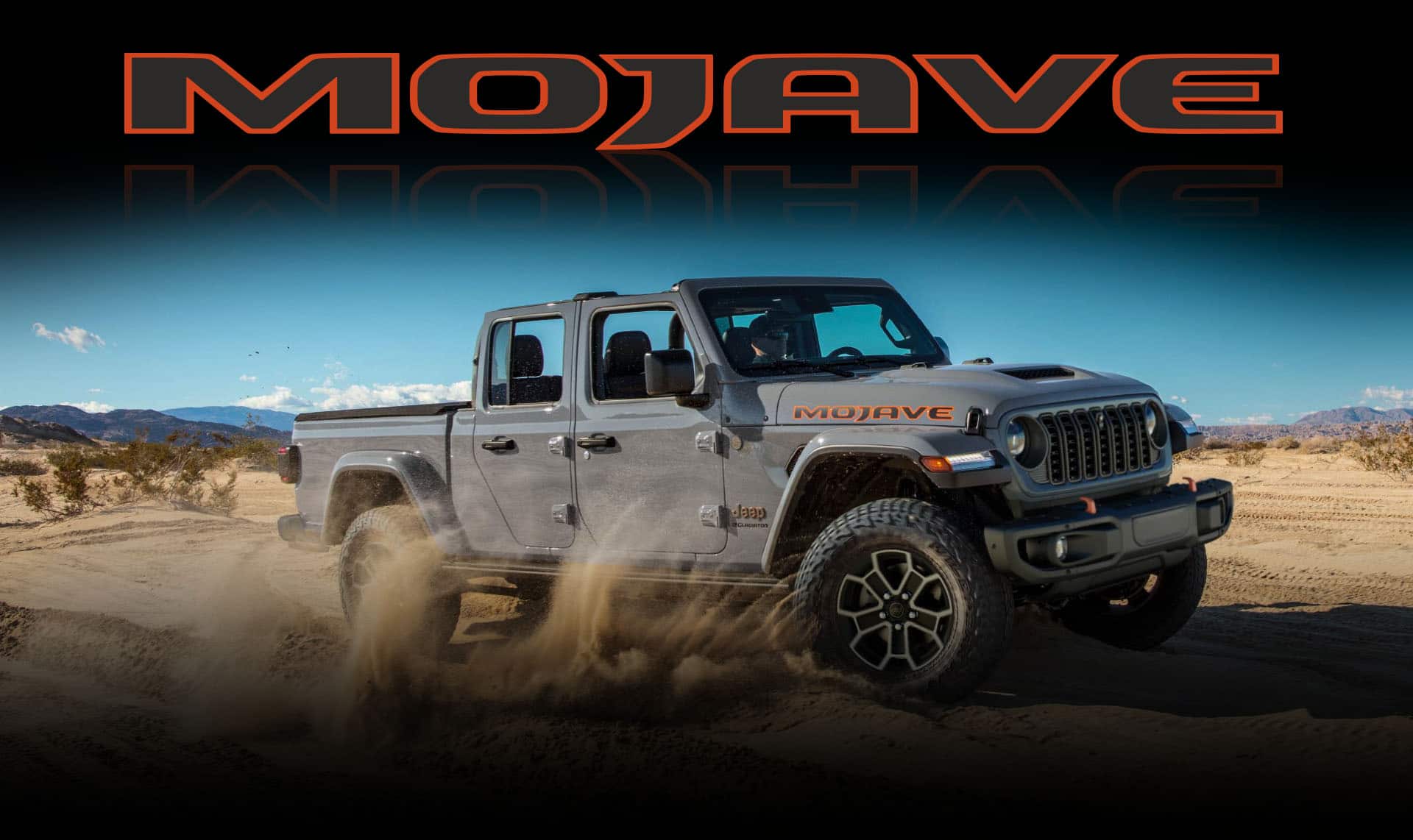 A gray 2024 Jeep Gladiator Mojave kicking up sand as it's driven off-road in the desert. Mojave.