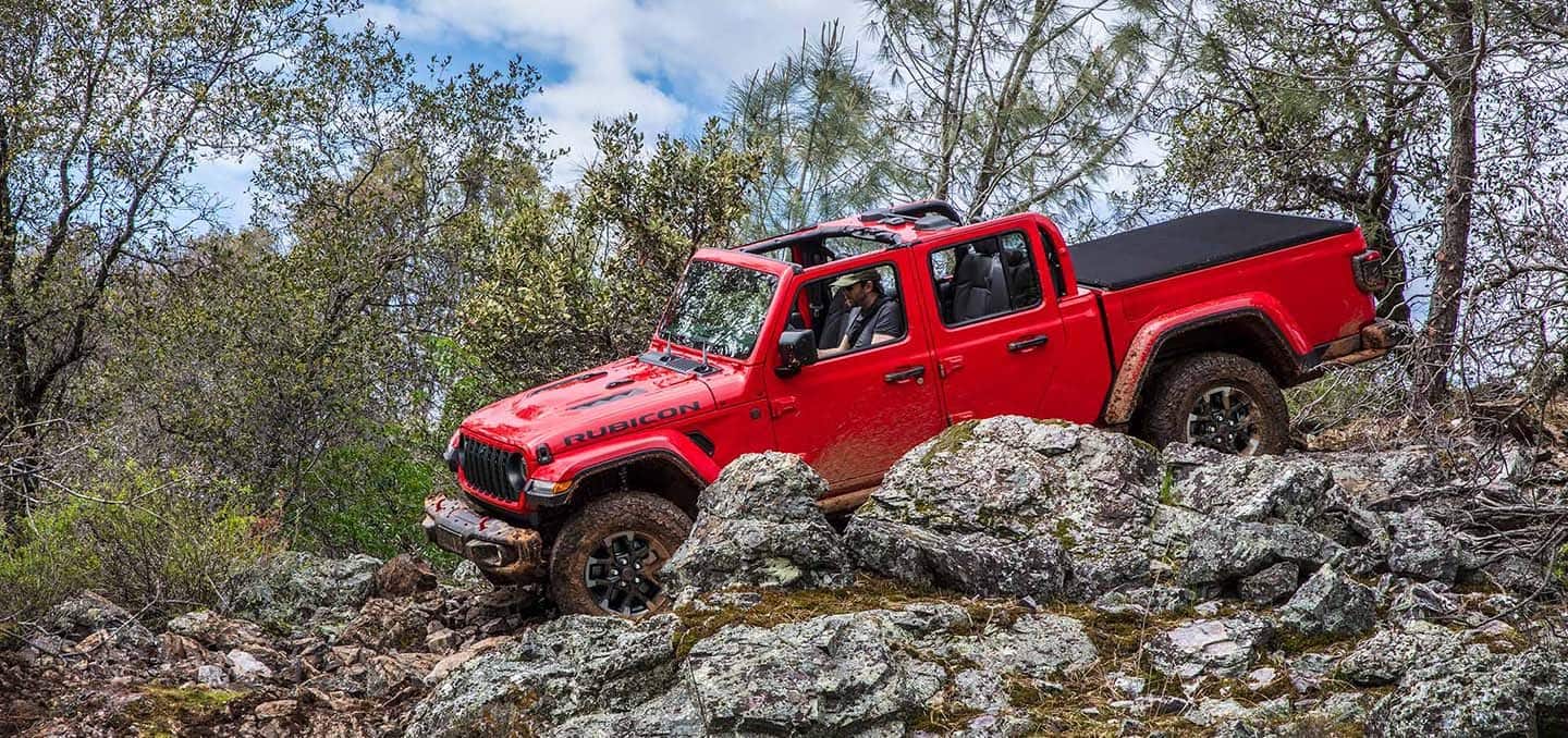 Red 2024 Jeep Gladiator Rubicon trail rated pickup truck rock crawling down rocky mountain side