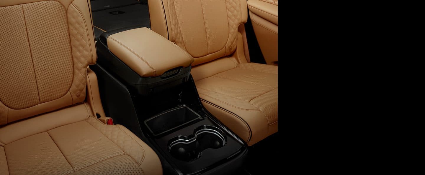 The second-row bucket seats with center console, armrest and cup holders in the 2024 Jeep Grand Cherokee L Summit Reserve.