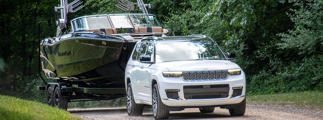 White Jeep Grand Cherokee towing a large black bow rider boat