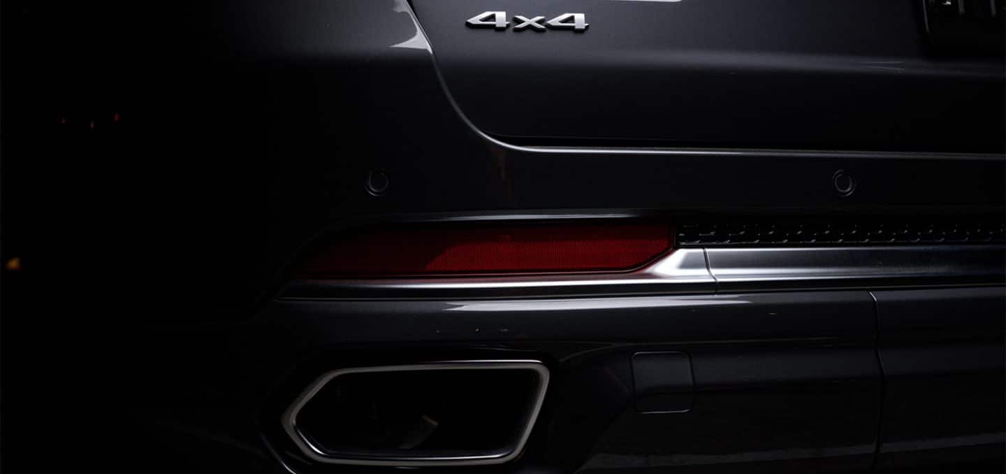 Display The entire 2025 Jeep Grand Cherokee Summit Reserve shrouded in darkness except for the liftgate 4x4 badge, driver-side taillamp and exhaust pipe.