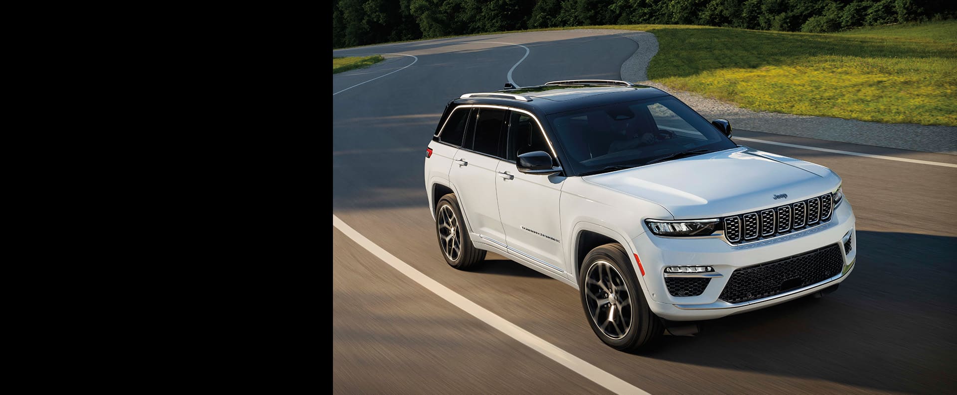 Un Jeep Grand Cherokee Summit Reserve 2024 blanco circulando por una carretera con curvas.