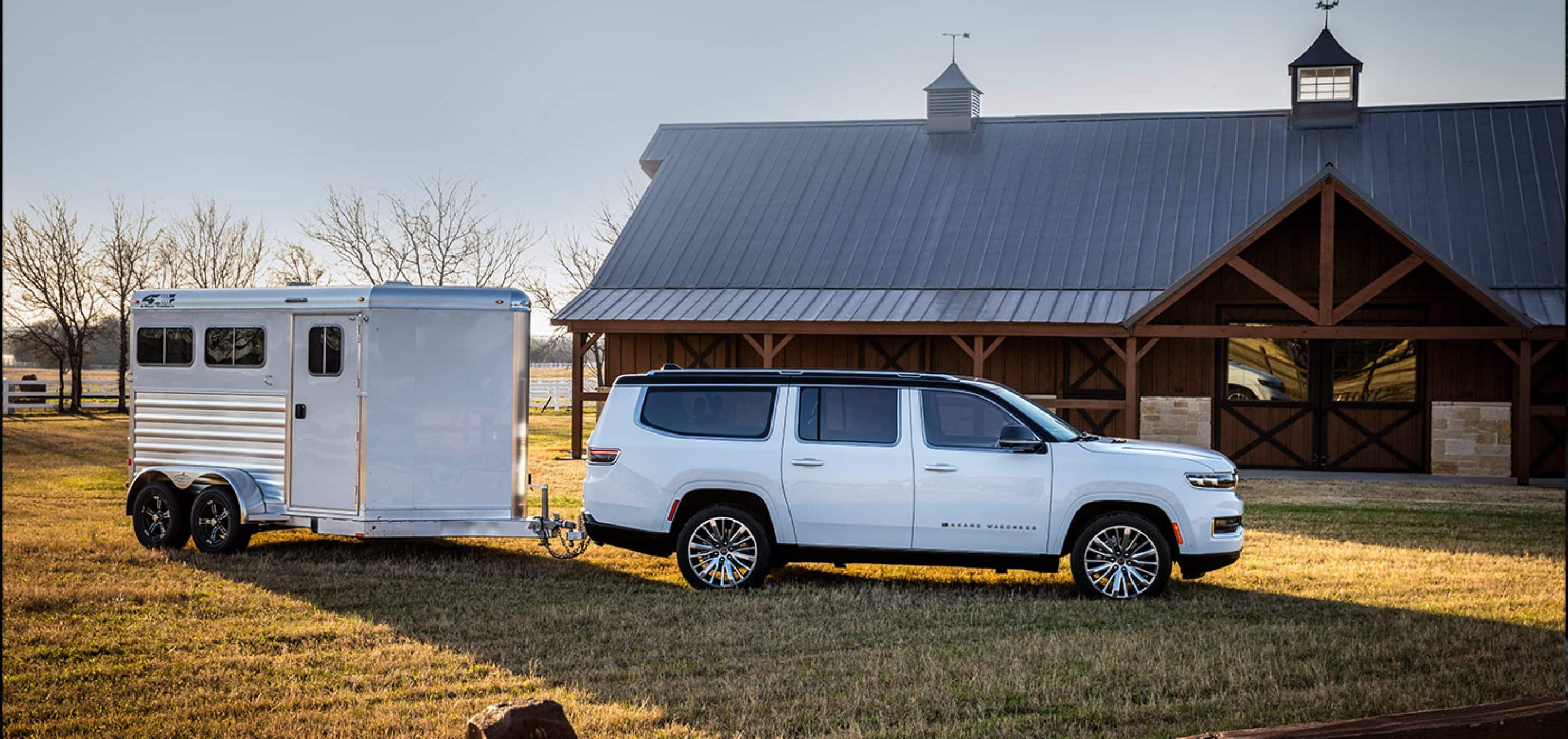 2024 jeep grand wagoneer towing trailer in front of farm cabin. 