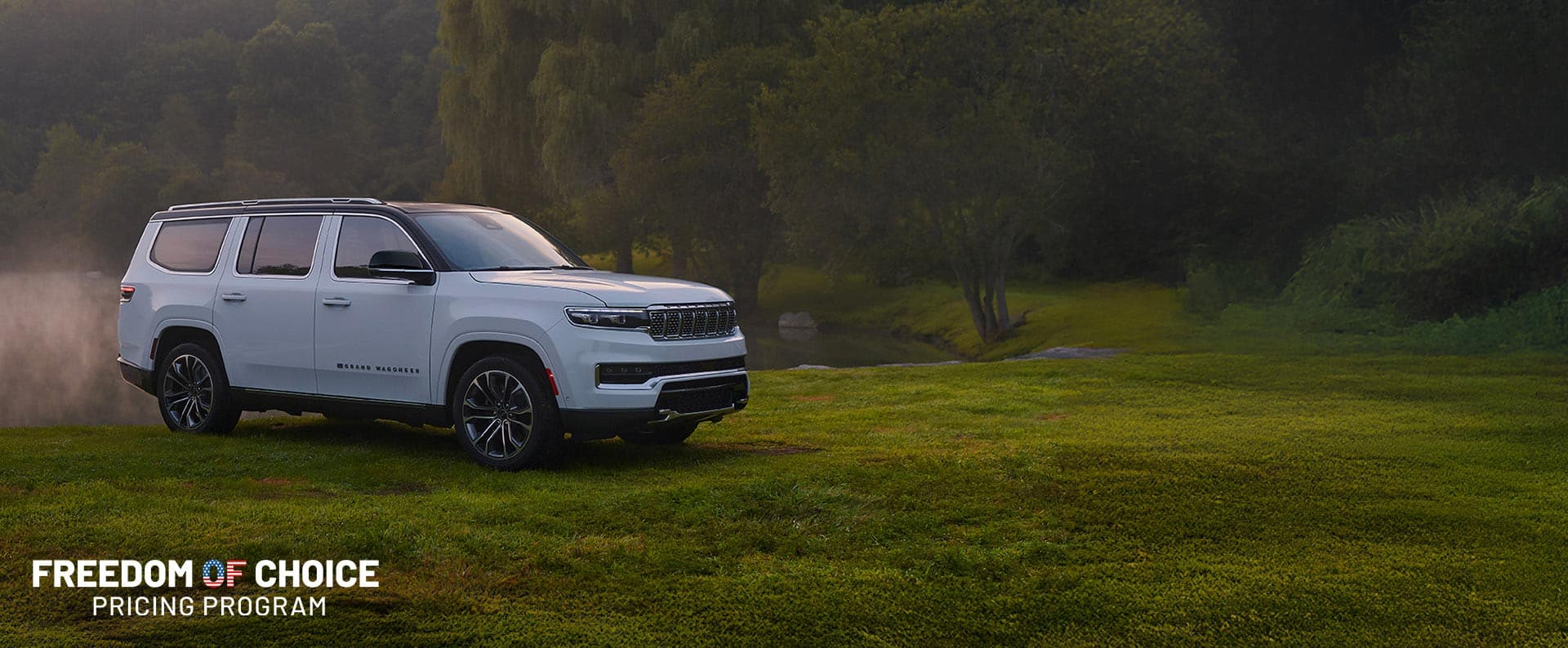 A white 2024 Jeep Grand Wagoneer L series 3 parked on the grass besides a pong blanketed in fog. Freedom of Choice Pricing Program.