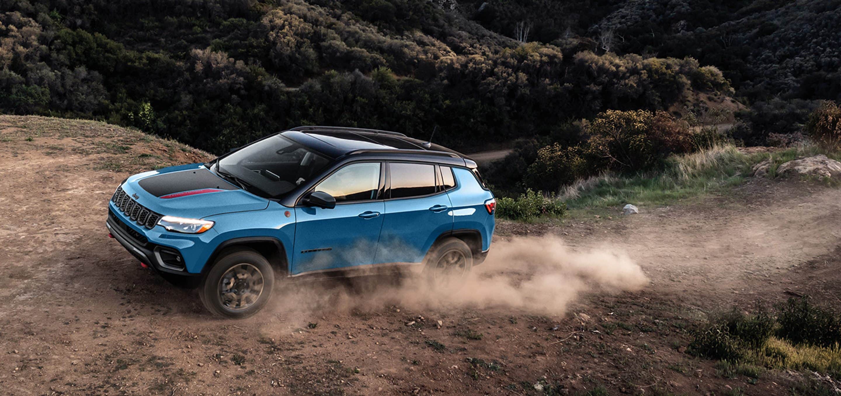 2025 Jeep Compass in blue and black accents driving on rocky terrain