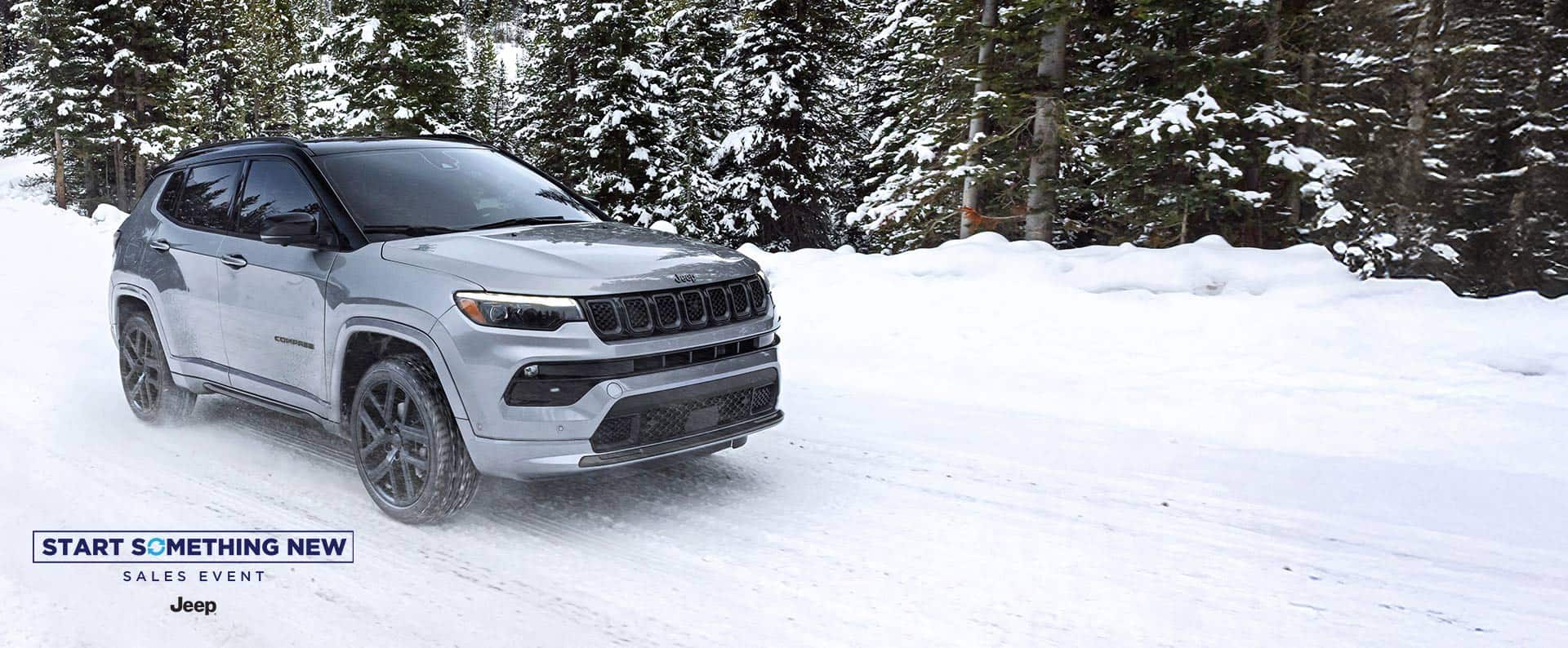 A silver 2025 Jeep Compass Limited with High Altitude Package, traveling on a snow-covered trail in the woods. The Start Something New Sales Event. Jeep.