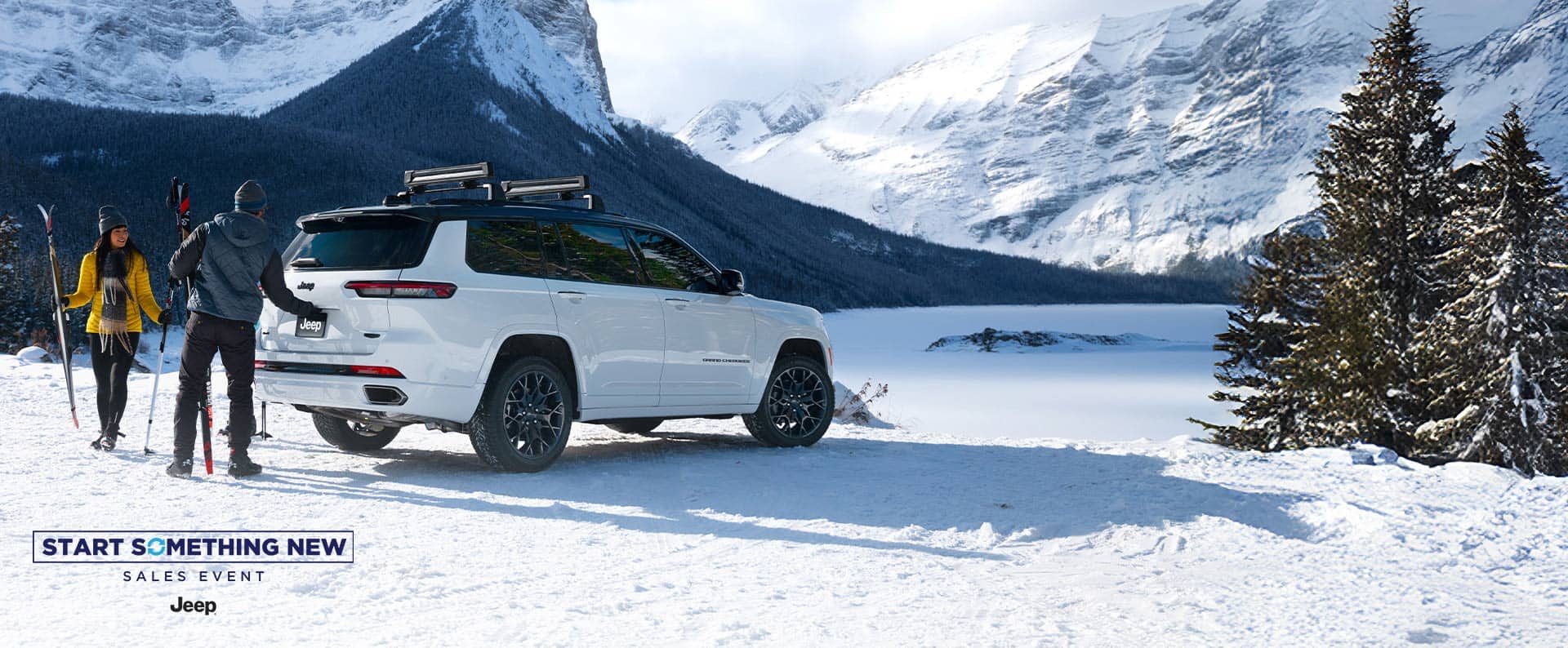 A white 2026 Jeep Grand Cherokee L High Altitude parked on a snow-covered clearing in the mountains. A couple nearby is carrying skiing equipment, and the man is about to open the liftgate. The Start Something New Sales Event. Jeep.