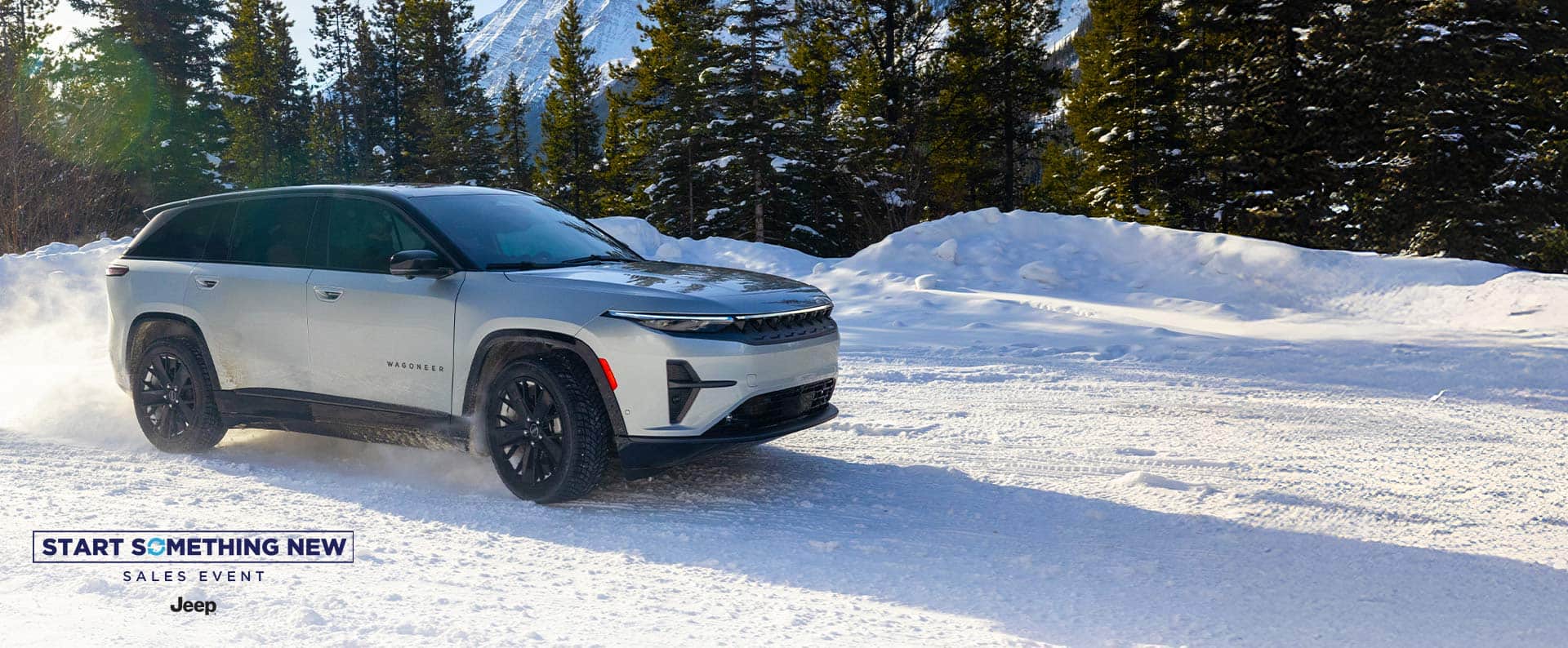 A silver 2025 Jeep Wagoneer S Launch Edition traveling on a snow-covered road in a forest with mountains in the background. The Start Something New Sales Event. Jeep.