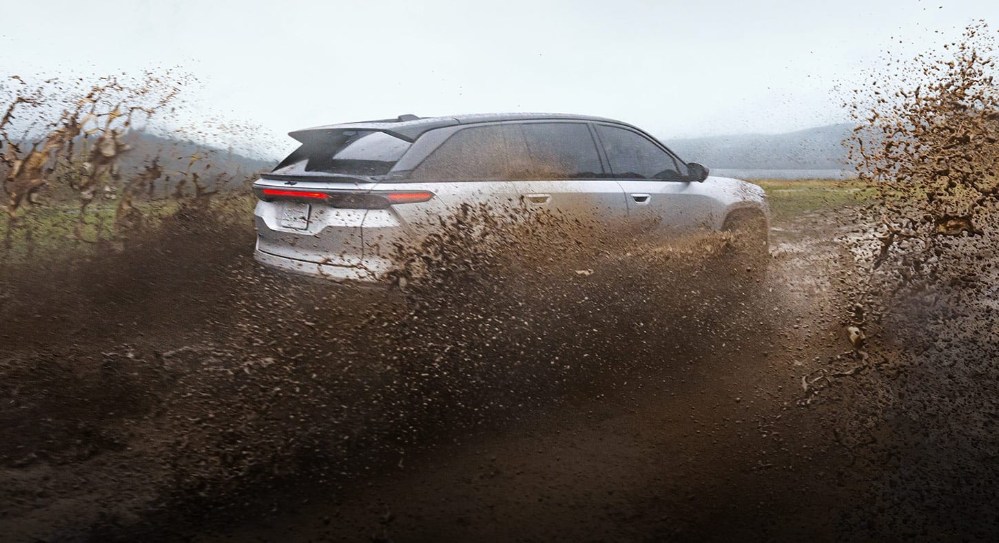 A silver 2025 Jeep Wagoneer S Launch Edition traveling through a mucky trail, kicking up mud as it goes.
