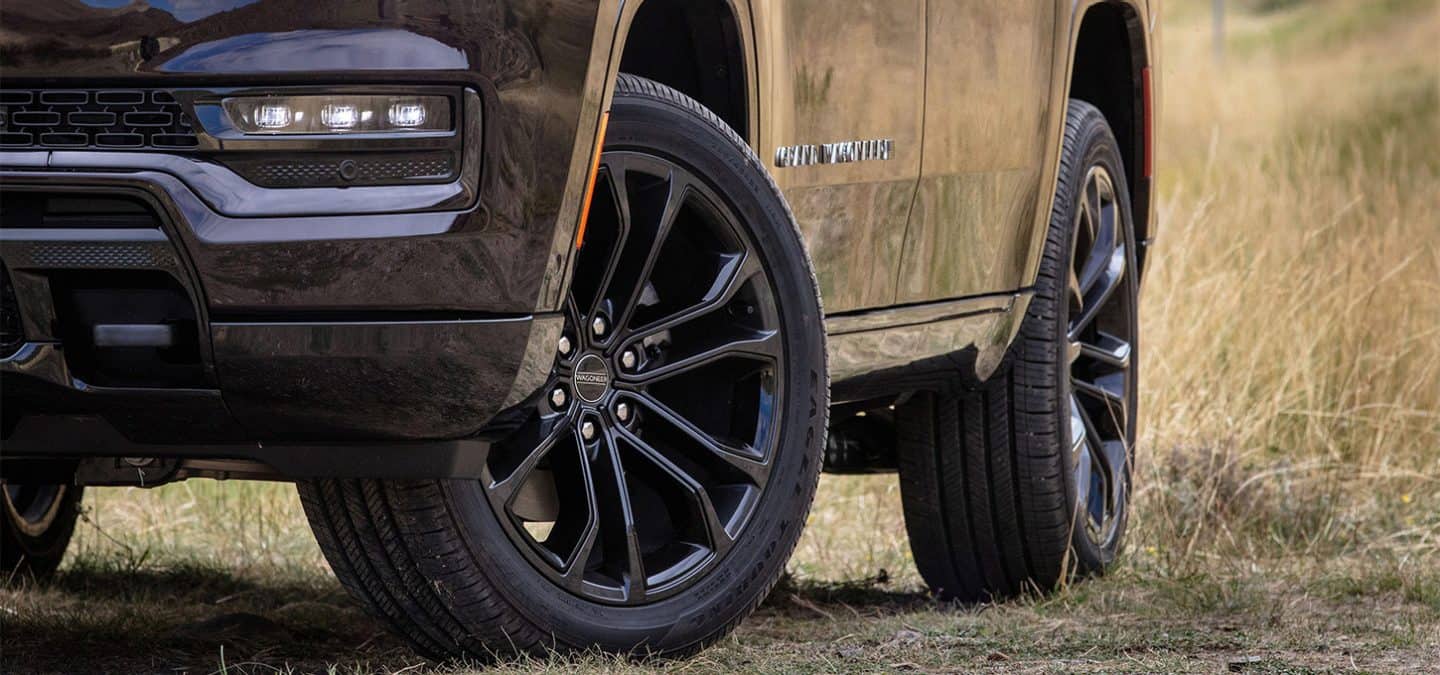 Display The driver-side front and rear wheels on a black 2025 Jeep Grand Wagoneer Obsidian.