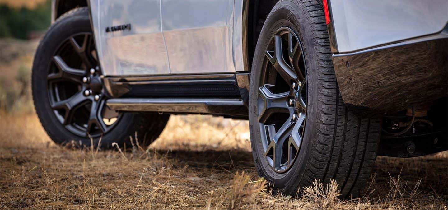 Display The driver-side front and rear wheels on a white 2025 Jeep Wagoneer Carbide.