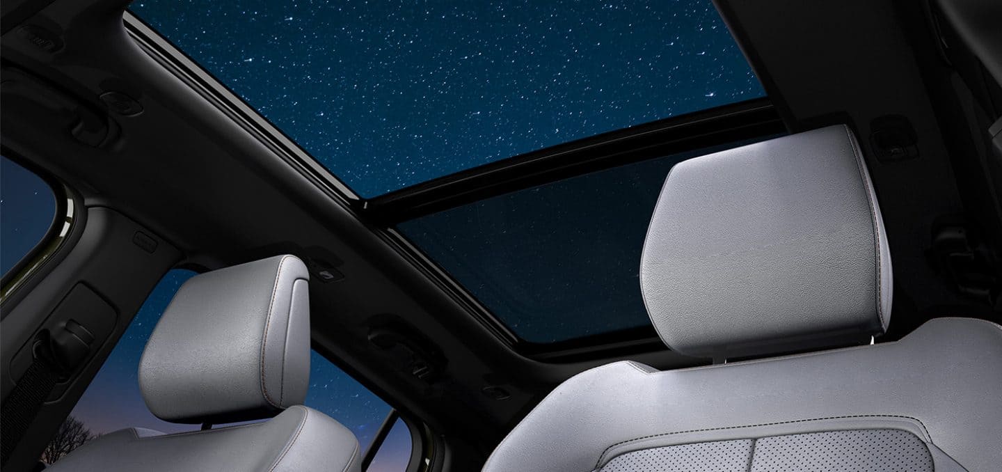 Display The sunroof open from inside a 2026 Jeep Cherokee revealing a starry night sky.