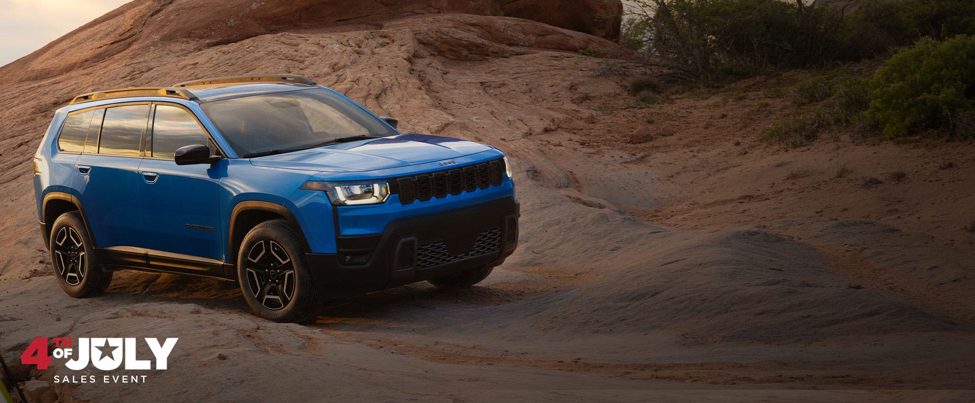 A blue 2026 Jeep Cherokee Laredo parked on a trail off-road. 4th of July Sales Event.