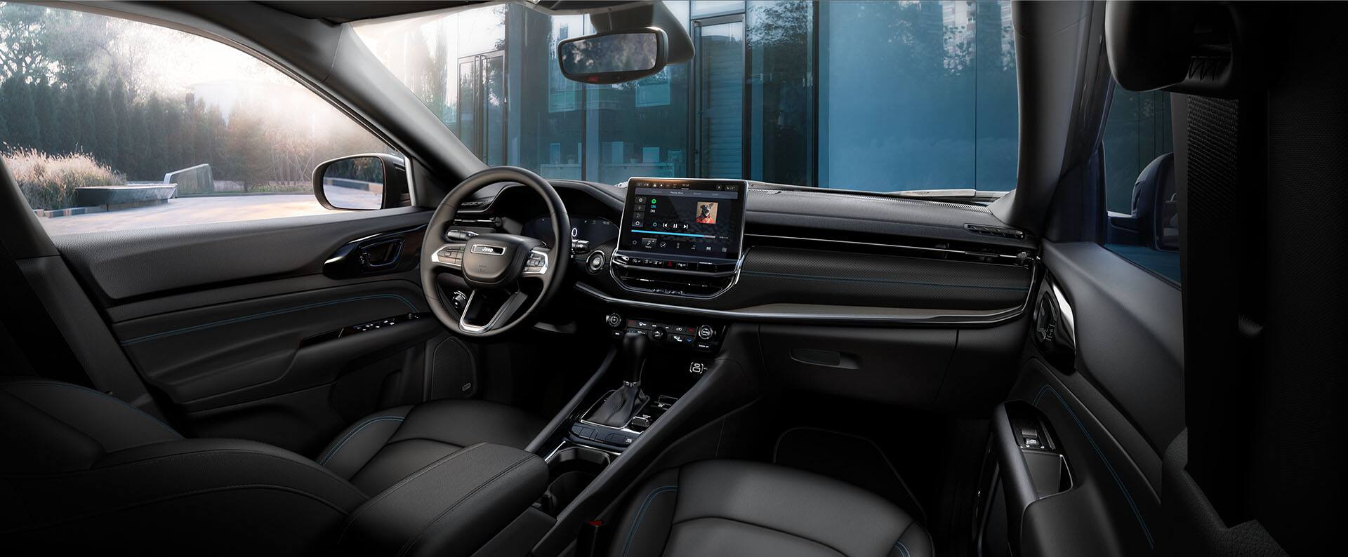 The front seat area in the 2026 Jeep Compass, focusing on the seats, steering wheel, Digital Cluster Display, Uconnect touchscreen and center stack controls.
