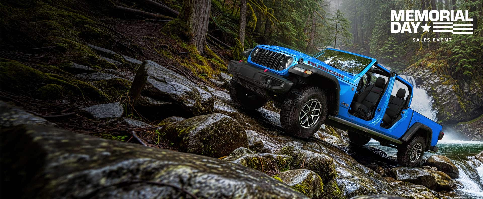 A blue 2026 Jeep Gladiator Rubicon with its doors and top removed, parked on a rocky hill, just above a stream. Memorial Day Sales Event.