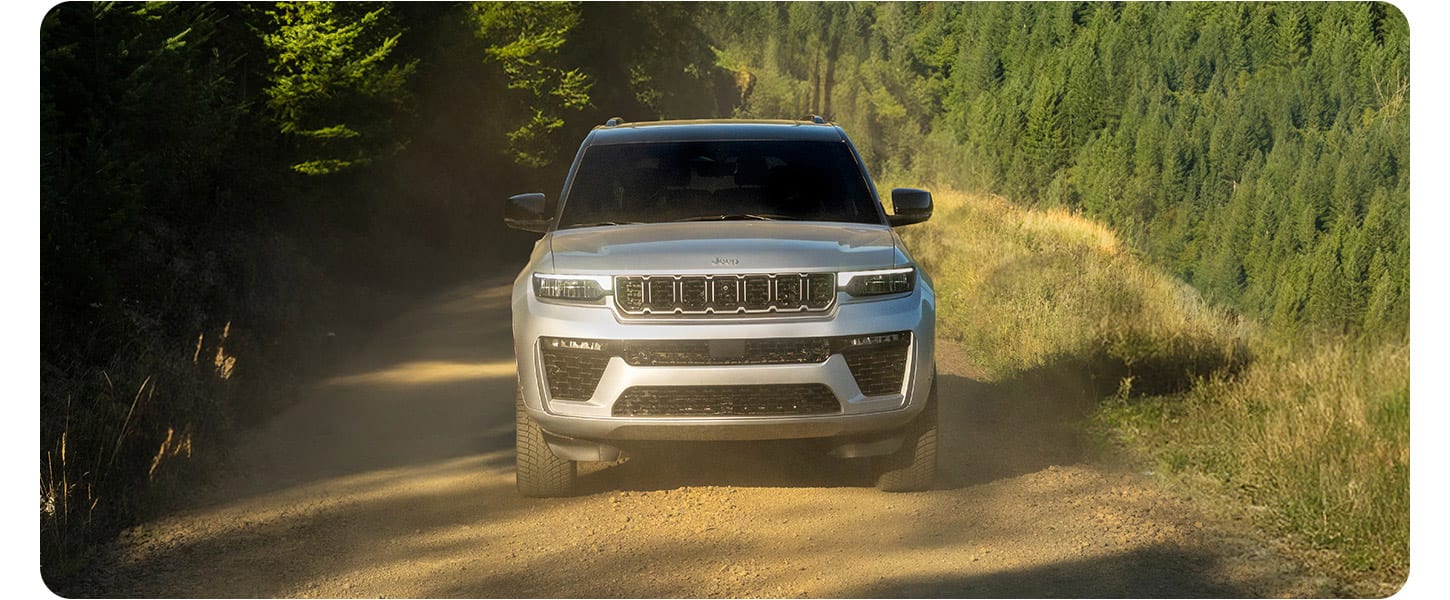 A silver 2026 Jeep Grand Cherokee Summit traveling down a highway.