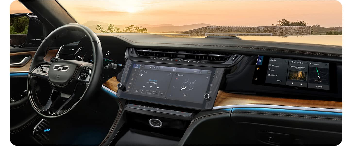 The steering wheel, Uconnect touchscreen, Front Passenger Interactive Touchscreen Display and wireless charging pad in the 2026 Jeep Grand Cherokee Summit.