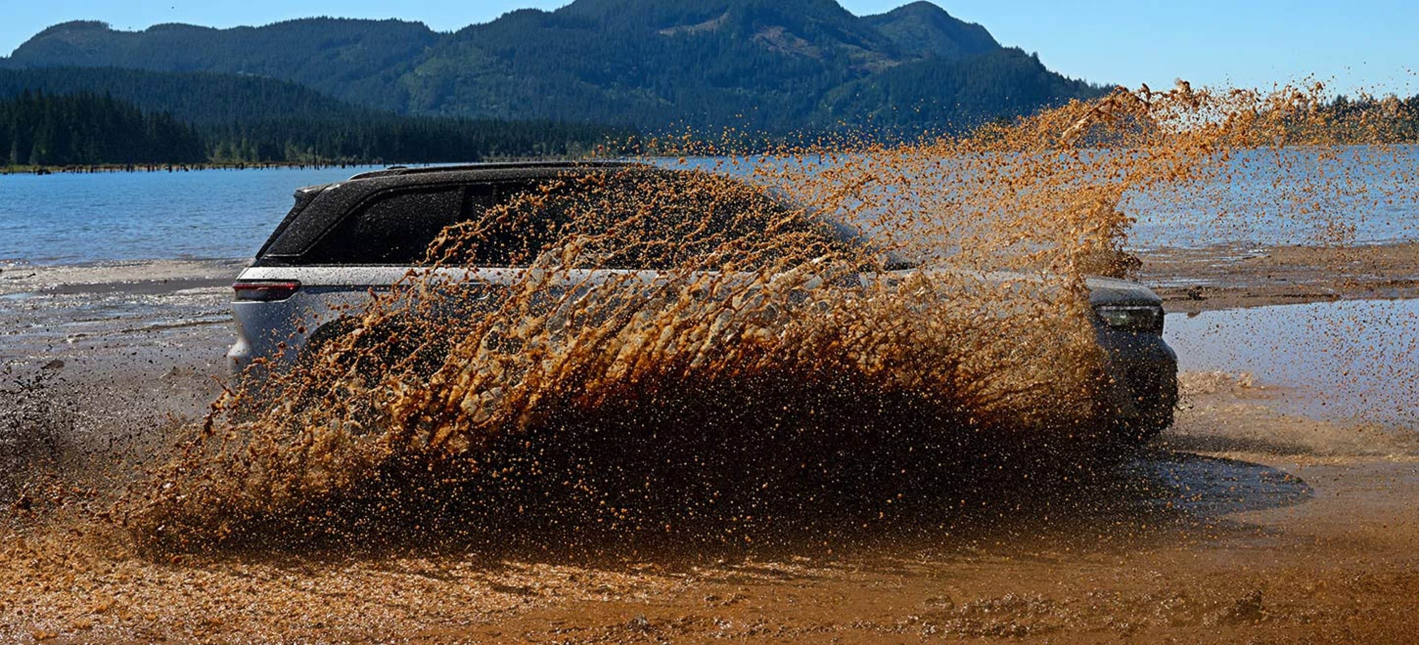 A 2026 Jeep Grand Cherokee throwing up mud on a lakeshore