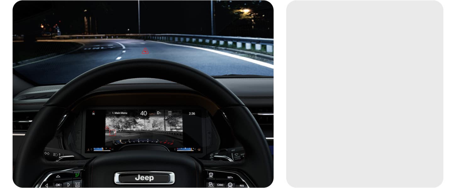 A dark highway ahead, visible through the windshield of the 2026 Jeep Grand Cherokee, as the Digital Cluster displays a thermal image of the same road with a deer standing beside it, not noticeable with the naked eye.