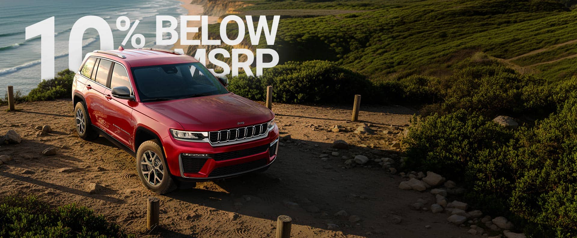 A red 2026 Jeep Grand Cherokee Limited parked on a beach near the shoreline. 520 + Miles. Drive Into Fall America’s Sales Event.