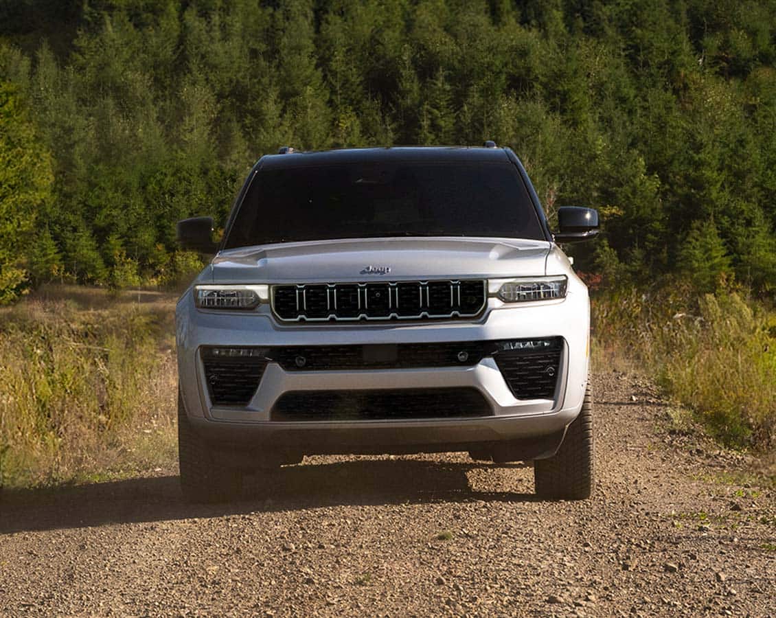 Silver Jeep Grand Cherokee driving on a gravel road