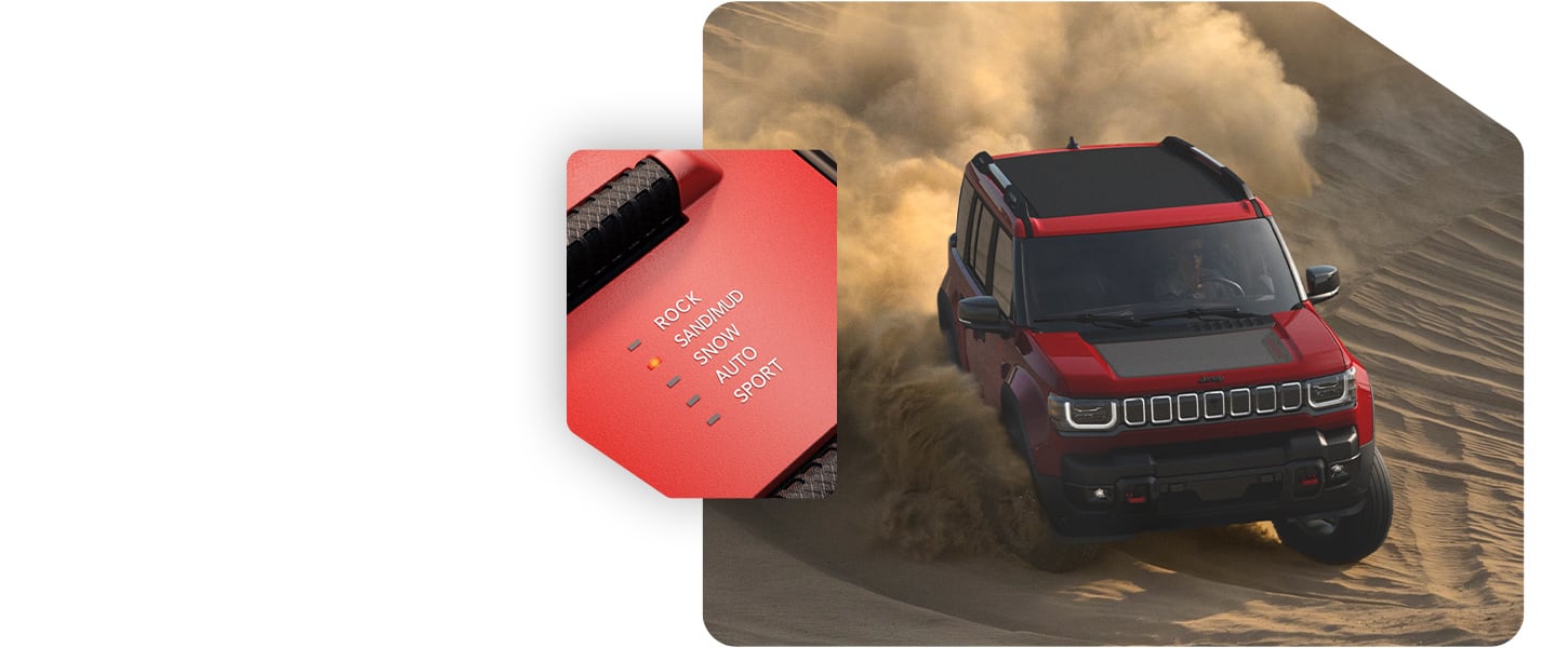 A red 2026 Jeep Recon Moab descending a large dune and the Selec-Terrain Traction Management System drive mode set on Sand/Mud.