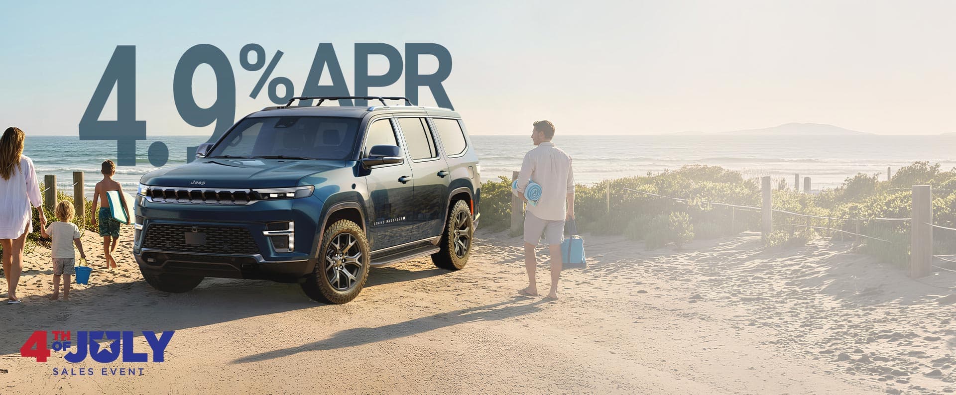 Un Grand Wagoneer Upland 2026 azul estacionado en la playa y una familia de cuatro personas que se dirigen hacia el agua cargando sus cosas de playa. Evento de ventas del 4 de julio.