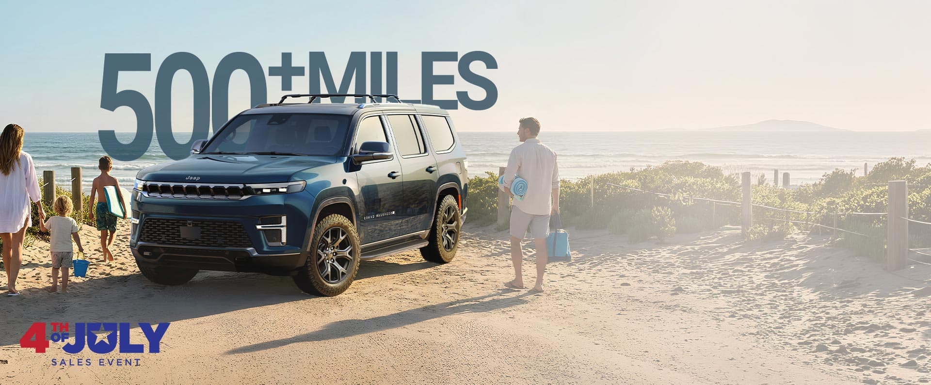 Un Grand Wagoneer Upland 2026 azul estacionado en la playa y una familia de cuatro personas que se dirigen hacia el agua cargando sus cosas de playa. Evento de ventas del 4 de julio.