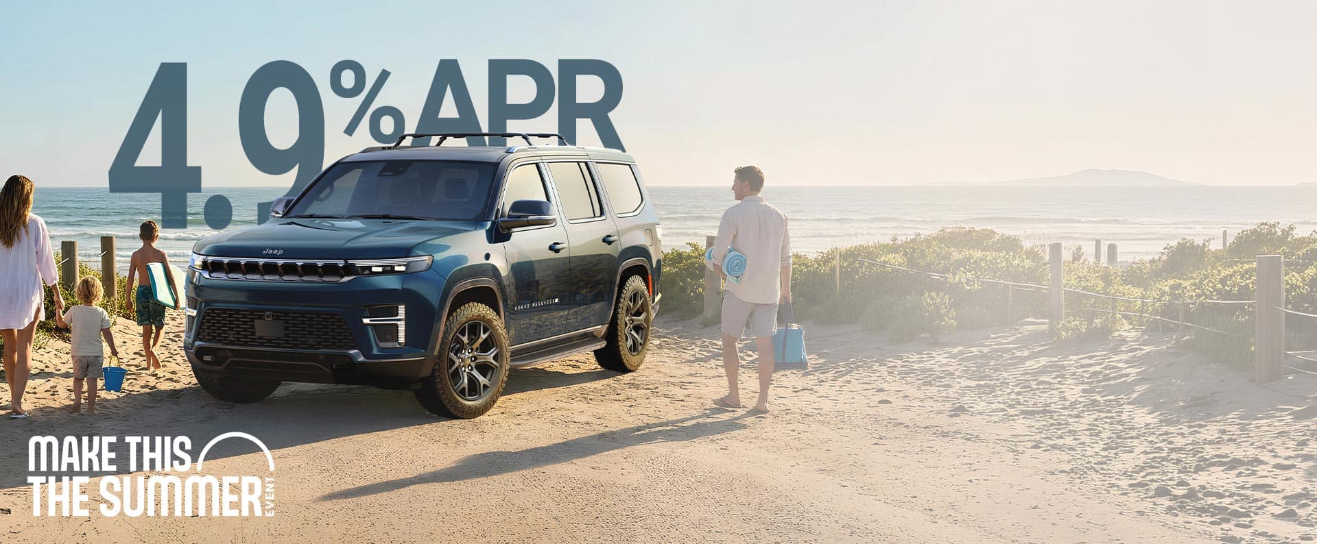 A blue 2026 Grand Wagoneer Upland parked at the beach with a family of four heading toward the water carrying beach gear. Make This The Summer Event.